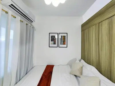 a bedroom with a bed with white walls and a window at 1BR Condotel with Balcony at FAME Residences #FM06-1 in Manila