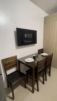 a dining room with a table and chairs and a television at Shore Residences Tower D in Manila