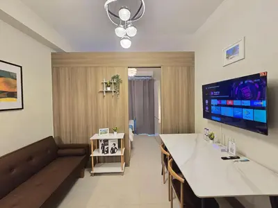 a living room with a long table and a couch at 1BR Condotel with Balcony at FAME Residences #FM10-1 in Manila