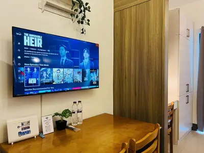 a television hanging on a wall above a wooden table at 1BR Condotel with Balcony at FAME Residences #FM12-1 in Manila