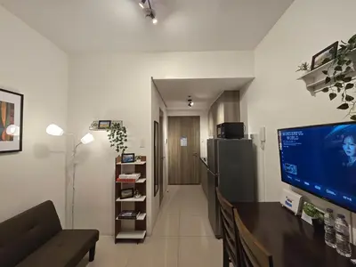 a living room with a tv and a couch and a refrigerator at 1BR Condotel with Balcony at FAME Residences #FM13-1 in Manila
