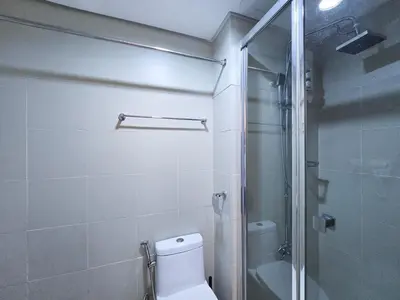 a bathroom with a toilet and a glass shower at 1BR Condotel with Balcony at FAME Residences #FM13-1 in Manila