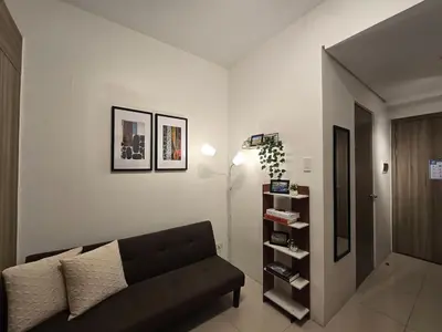 a living room with a couch and a book shelf at 1BR Condotel with Balcony at FAME Residences #FM13-1 in Manila