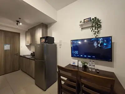 a kitchen with a table and a television on the wall at 1BR Condotel with Balcony at FAME Residences #FM13-1 in Manila