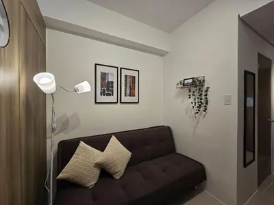 a living room with a black couch and a lamp at 1BR Condotel with Balcony at FAME Residences #FM14-1 in Manila