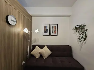 a living room with a couch and a clock on the wall at 1BR Condotel with Balcony at FAME Residences #FM14-1 in Manila