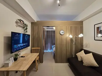 a living room with a couch and a table and a television at 1BR Condotel with Balcony at FAME Residences #FM14-1 in Manila