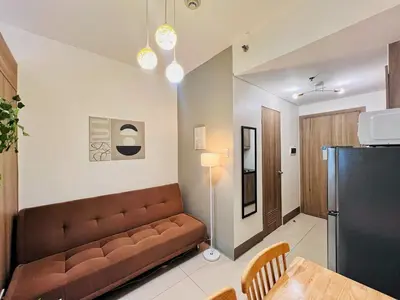 a living room with a brown couch and a table at 1BR Condotel with Balcony at FAME Residences #FM15-1 in Manila