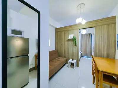 a kitchen and a living room with a table and a refrigerator at 1BR Condotel with Balcony at FAME Residences #FM18-1 in Manila