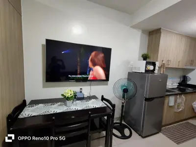 a kitchen with a small table with a television on the wall at JAO Cozy Stay - Mall of Asia in Sampong