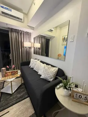 a living room with a black couch and a table at ElcaPri Staycation - Shore 3 Residences in Manila