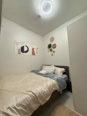 a bed in a bedroom with a white wall at ElcaPri Staycation - Shore 3 Residences in Manila