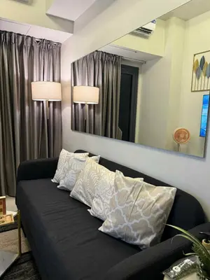a black couch in a living room with a mirror at ElcaPri Staycation - Shore 3 Residences in Manila