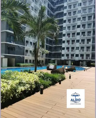 a swimming pool with palm trees and a large building at Mall of Asia condotel shore 3 residence 3 in Manila