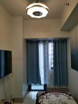 a bedroom with a bed and a window with blue curtains at Mall of Asia condotel shore 3 residence 3 in Manila