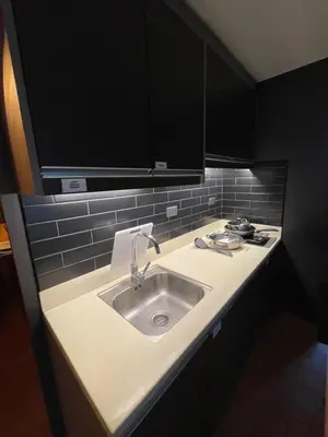 a kitchen with a sink and black cabinets at Makati City The Serenity Tower 2512A in Manila