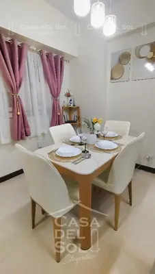 a dining room with a table and white chairs at Casa Del Sol Staycation in Manila