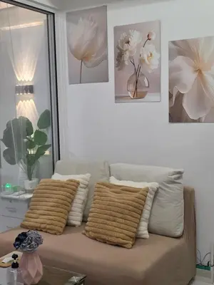 a couch in a living room with pictures on the wall at Casa Serenity Staycation at Azure parañaque with 1 bedroom good for 1 to 4 pax airconditioned room and pool view near sm bicutan in Manila