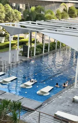 a pool at a hotel with people laying on surfboards at Casa Serenity Staycation at Azure parañaque with 1 bedroom good for 1 to 4 pax airconditioned room and pool view near sm bicutan in Manila