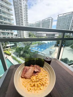 a plate of food on a table on a balcony at Casa Serenity Staycation at Azure parañaque with 1 bedroom good for 1 to 4 pax airconditioned room and pool view near sm bicutan in Manila