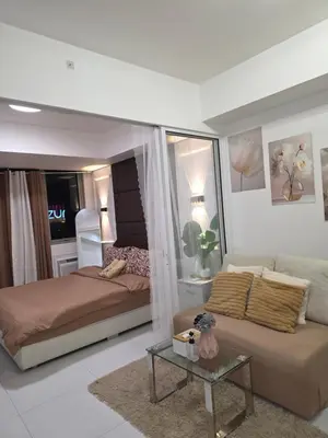 a bedroom with a bed and a couch and a table at Casa Serenity Staycation at Azure parañaque with 1 bedroom good for 1 to 4 pax airconditioned room and pool view near sm bicutan in Manila