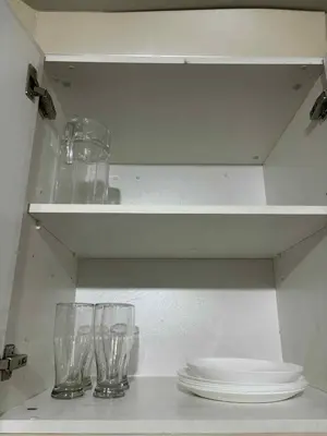 three empty wine glasses and plates on a shelf at Rqui Rooms Near airport and Newport World Resorts in Manila