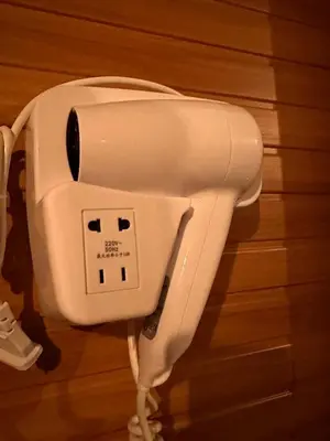 a white electric hair dryer hanging on a wall at Close dont book in Manila