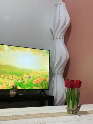 a living room with a television and a white vase with flowers at SMDC AIR Residences in Manila