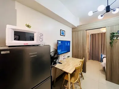 a kitchen with a refrigerator and a table with a tv at 1BR Condotel with Balcony at FAME Residences #FM19-1 in Manila