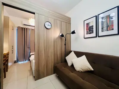 a living room with a couch and a clock on a wall at 1BR Condotel with Balcony at FAME Residences #FM20-1 in Manila