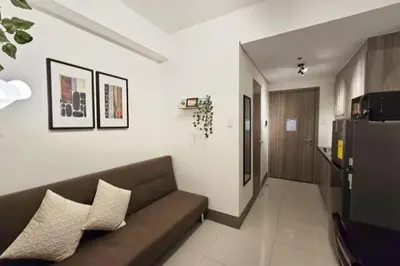a living room with a couch and a refrigerator at 1BR Condotel with Balcony at FAME Residences #FM21-1 in Manila