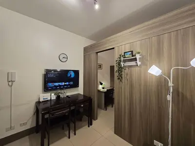 a living room with a table and a tv on the wall at 1BR Condotel with Balcony at FAME Residences #FM21-1 in Manila