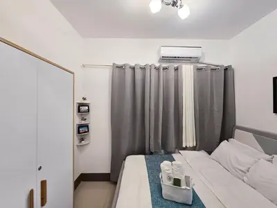 a small room with a bed with a mirror and a window at 1BR Condotel with Balcony at FAME Residences #FM23-1 in Manila