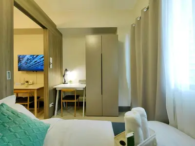 a bedroom with a bed and a desk and a table at 1BR Condotel with Balcony at FAME Residences #FM24-1 in Manila