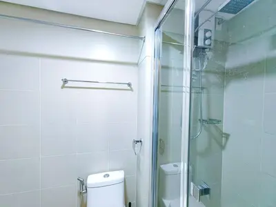 a bathroom with a toilet and a glass shower at 1BR Condotel with Balcony at FAME Residences #FM26-1 in Manila