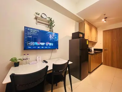 a kitchen with a table with chairs and a tv on the wall at 1BR Condotel with Balcony at FAME Residences #FM26-1 in Manila