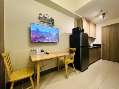 a kitchen with a table and a television on the wall at 1BR Condotel with Balcony at FAME Residences #FM27-1 in Manila