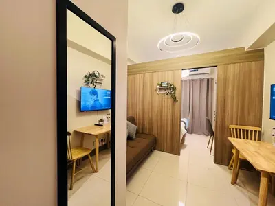 a living room and dining room with a mirror at 1BR Condotel with Balcony at FAME Residences #FM27-1 in Manila