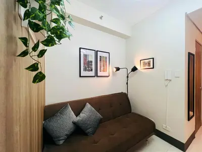 a living room with a couch and a plant at 1BR Condotel with Balcony at FAME Residences #FM28-1 in Manila