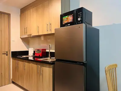 a kitchen with a stainless steel refrigerator with a microwave at 1BR Condotel with Balcony at FAME Residences #FM28-1 in Manila