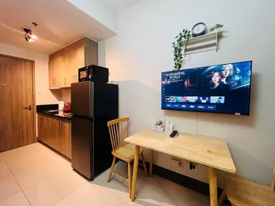a kitchen with a table and a black refrigerator at 1BR Condotel with Balcony at FAME Residences #FM28-1 in Manila