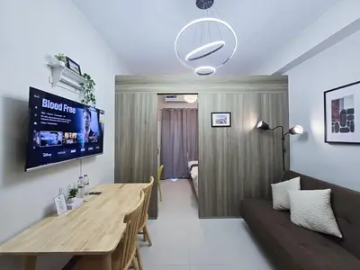a living room with a wooden table and a couch at 1BR Condotel with Balcony at FAME Residences #FM31-1 in Manila