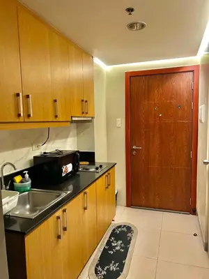 a kitchen with wooden cabinets and a sink and a door at Fika Staycation in Manila