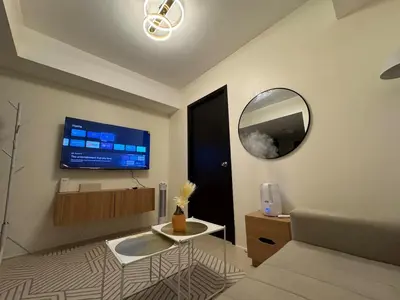 a living room with a couch and a tv on the wall at Reign Escape in Manila