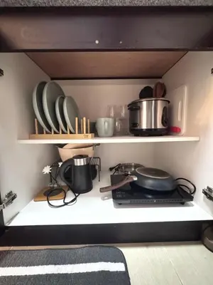 a kitchen shelf with plates and pots and pans at The Fresh Escape 2 in Manila