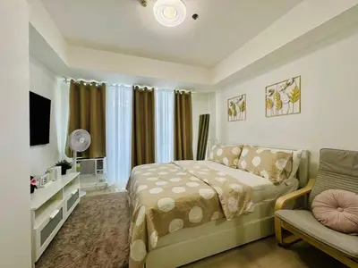 a bedroom with a bed and a couch and a television at SM Bicutan by Bahamas in Manila