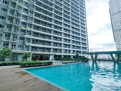 a swimming pool in front of a large building at 1BR Condotel with Balcony at FAME Residences #FM32-1 in Manila