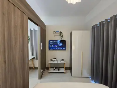 a living room with a television and a refrigerator at 1BR Condotel with Balcony at FAME Residences #FM34-1 in Manila