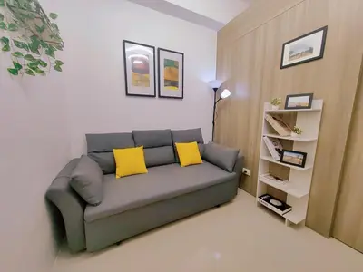 a living room with a couch with two yellow pillows at 1BR Condotel with Balcony at FAME Residences #FM36-1 in Manila