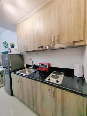 a kitchen with wooden cabinets and a counter top with a sink at 1BR Condotel with Balcony at FAME Residences #FM36-1 in Manila